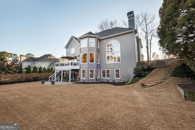 back of property with fence private yard, stairs, a lawn, a wooden deck, and a chimney