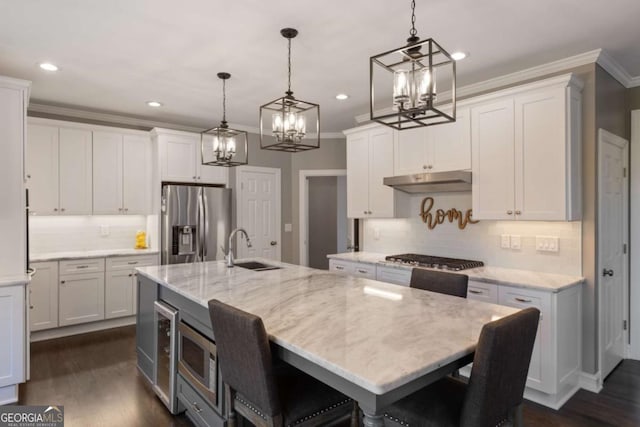 kitchen featuring under cabinet range hood, appliances with stainless steel finishes, dark wood-style flooring, and a sink