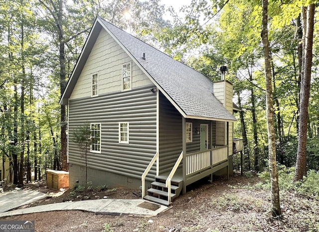 view of front of house featuring a shingled roof, crawl space, and a chimney