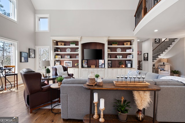 living area featuring a high ceiling, stairway, and wood finished floors