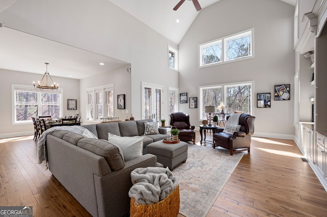 living room featuring baseboards, wood-type flooring, ceiling fan with notable chandelier, vaulted ceiling, and recessed lighting