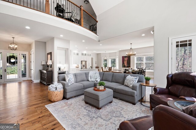 living room featuring a notable chandelier, recessed lighting, a high ceiling, light wood-type flooring, and baseboards