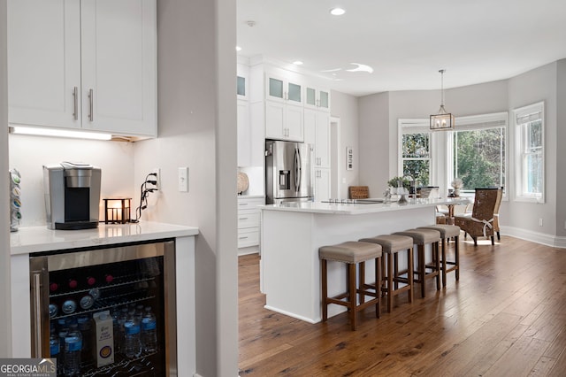 kitchen with a breakfast bar, dark wood-style floors, stainless steel fridge, and beverage cooler