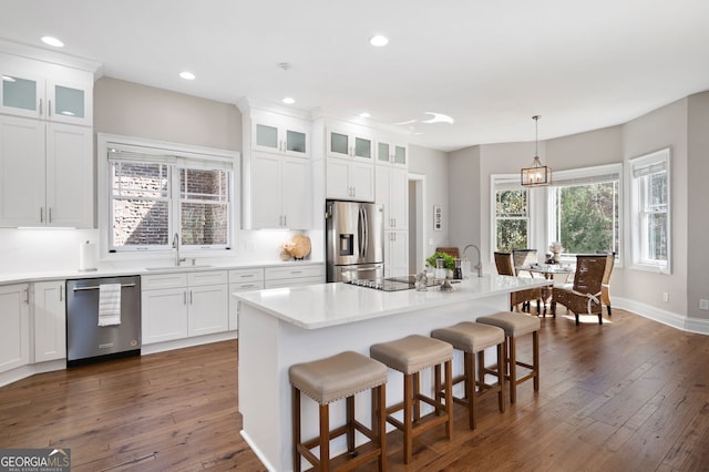 kitchen with appliances with stainless steel finishes, dark wood finished floors, a sink, and an island with sink