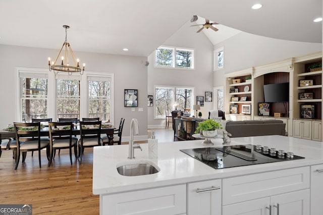 kitchen with light wood-style flooring, open floor plan, black electric stovetop, a sink, and recessed lighting