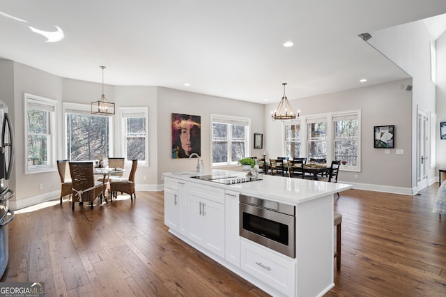 kitchen with dark wood-style floors, white cabinetry, built in microwave, and a chandelier