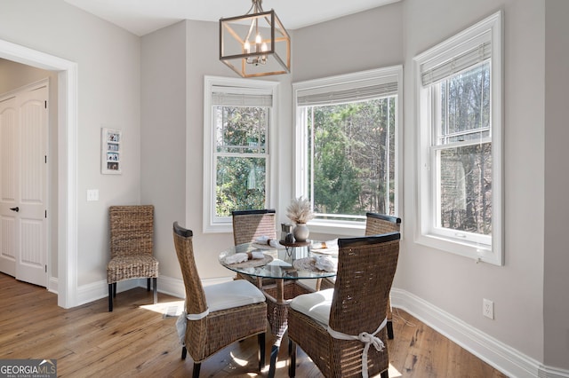 dining space with baseboards, a chandelier, and wood finished floors