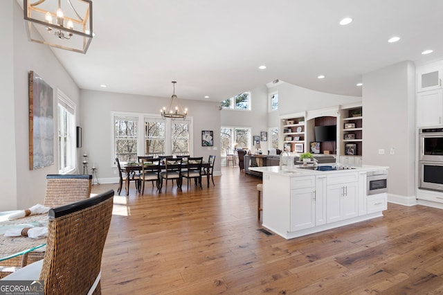 kitchen with a chandelier, double oven, light wood-style flooring, and white cabinetry