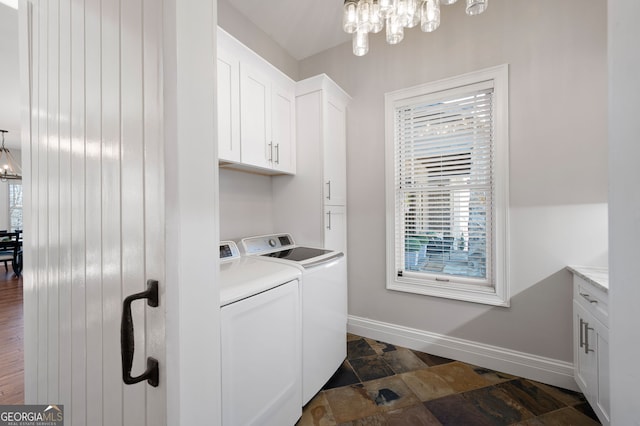 clothes washing area with stone finish flooring, independent washer and dryer, cabinet space, and baseboards