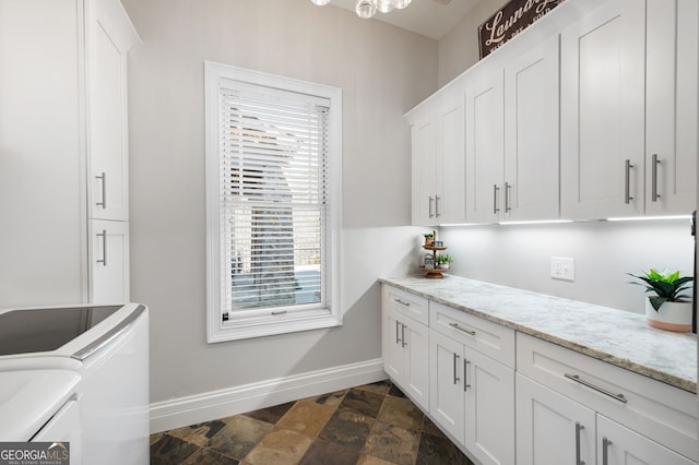 interior space with stone finish flooring, separate washer and dryer, cabinet space, and baseboards