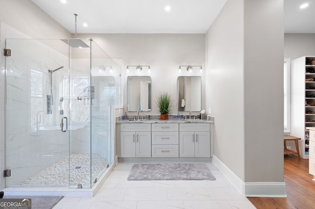 bathroom with recessed lighting, a sink, baseboards, a marble finish shower, and double vanity