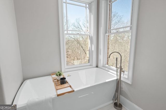 bathroom with a freestanding bath and baseboards