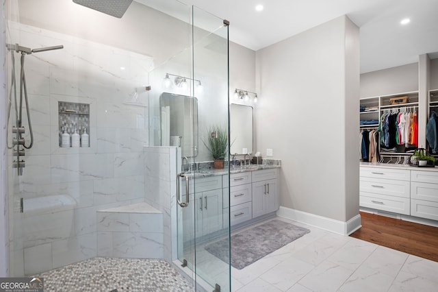 full bathroom with vanity, baseboards, marble finish floor, a spacious closet, and a stall shower