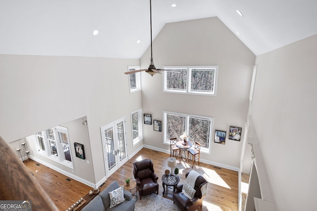 living area with a ceiling fan, french doors, plenty of natural light, and wood finished floors