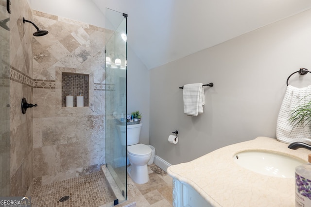 bathroom featuring lofted ceiling, toilet, a tile shower, vanity, and baseboards