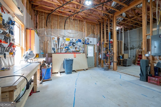 below grade area featuring a healthy amount of sunlight, electric panel, and a workshop area