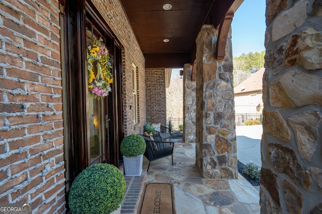 property entrance featuring a porch and brick siding