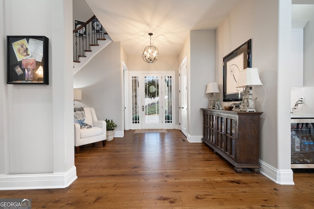 foyer with wood-type flooring, baseboards, and an inviting chandelier