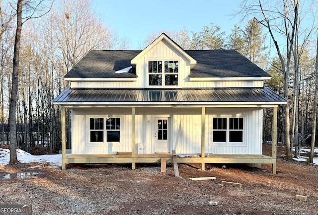 modern farmhouse with covered porch, metal roof, board and batten siding, and roof with shingles