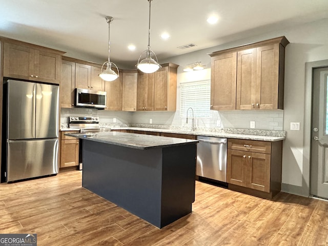 kitchen with a center island, tasteful backsplash, visible vents, light wood-style flooring, and appliances with stainless steel finishes