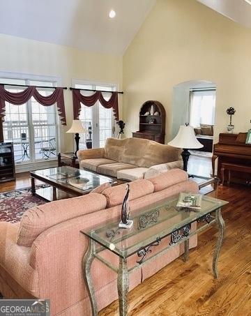 living room with high vaulted ceiling and wood finished floors