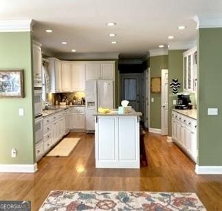 kitchen featuring white fridge with ice dispenser, a center island, crown molding, and wood finished floors