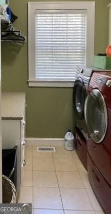 clothes washing area featuring light tile patterned floors, laundry area, separate washer and dryer, and visible vents