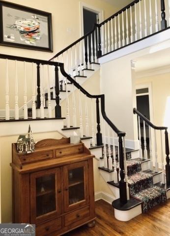 stairs with ornamental molding, a high ceiling, and wood finished floors