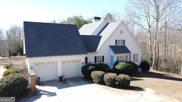 view of front of property featuring driveway, a shingled roof, a chimney, and an attached garage