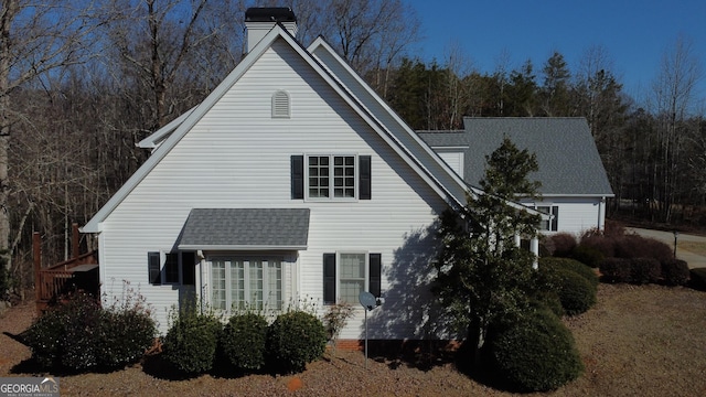 view of front of house with a shingled roof and a chimney