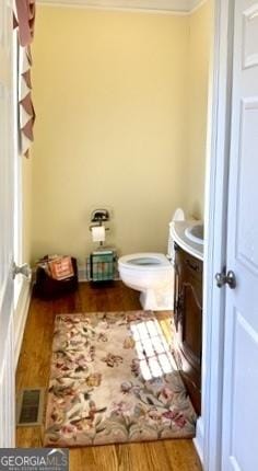 bathroom with toilet, wood finished floors, vanity, and visible vents