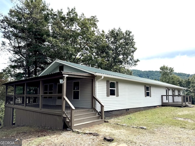 view of front facade with covered porch, metal roof, and crawl space