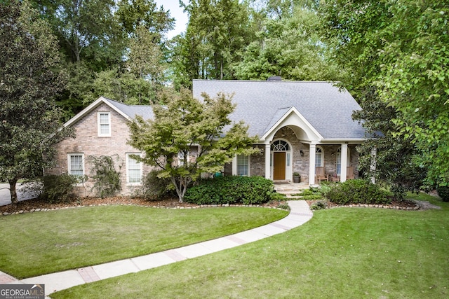 view of front of property with brick siding, a shingled roof, and a front yard