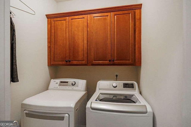 clothes washing area with independent washer and dryer and cabinet space