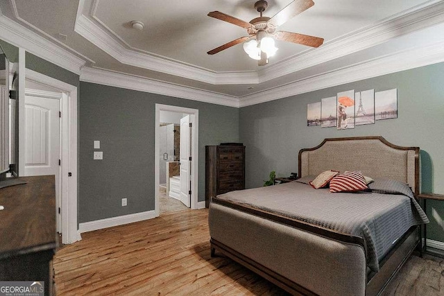 bedroom with ornamental molding, a tray ceiling, baseboards, and light wood-style floors