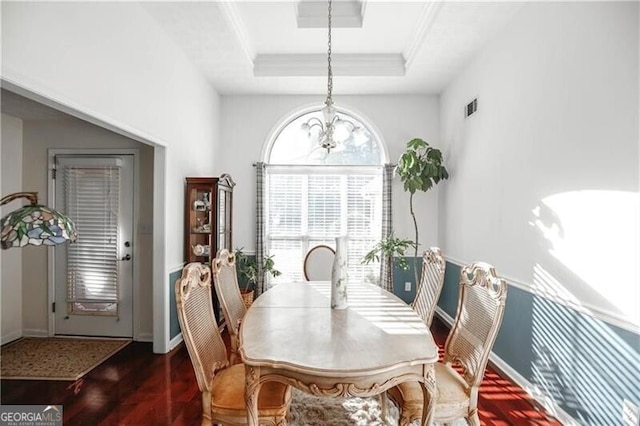 dining area with a tray ceiling, crown molding, visible vents, wood finished floors, and baseboards