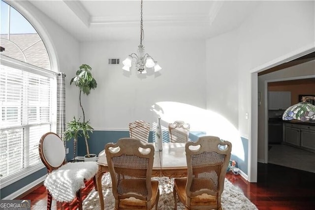 dining area featuring wood finished floors, visible vents, baseboards, a raised ceiling, and an inviting chandelier