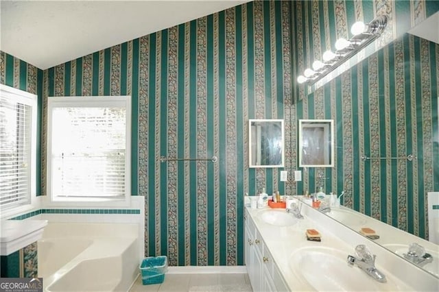 full bathroom featuring a bath, wallpapered walls, a sink, and tile patterned floors