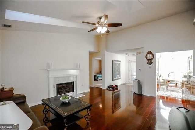 living room with visible vents, a ceiling fan, lofted ceiling, a premium fireplace, and wood finished floors