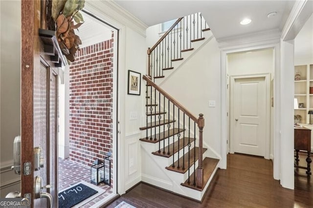 entrance foyer featuring dark wood-style floors, ornamental molding, and stairs