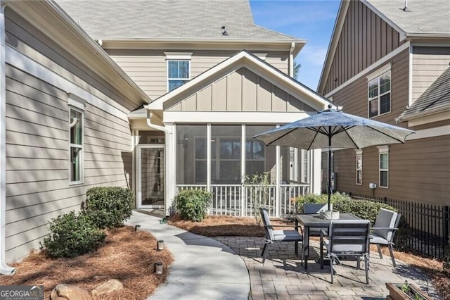 back of property with a patio, a shingled roof, fence, a sunroom, and board and batten siding