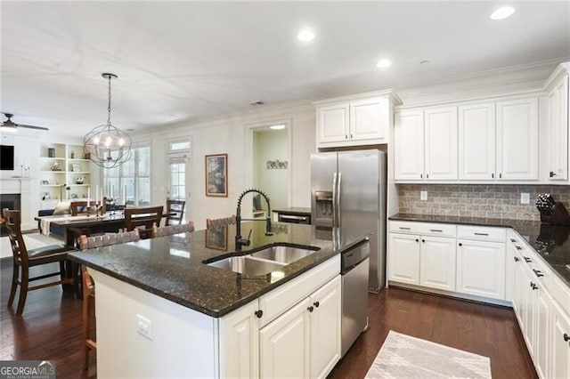 kitchen with dark wood-style flooring, stainless steel appliances, open floor plan, white cabinets, and a sink