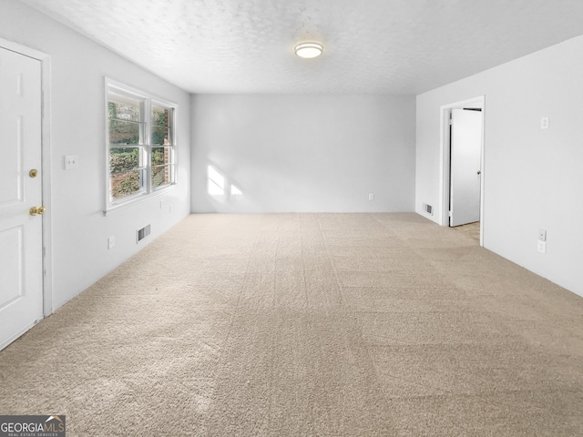 carpeted spare room with a textured ceiling and visible vents