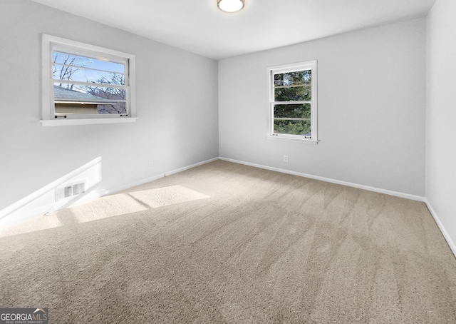 empty room with carpet, visible vents, and baseboards