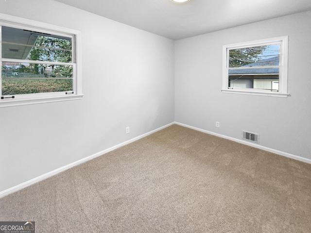 spare room featuring carpet, visible vents, and baseboards