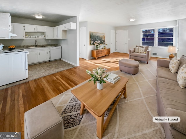 living area with light wood-type flooring, visible vents, and baseboards