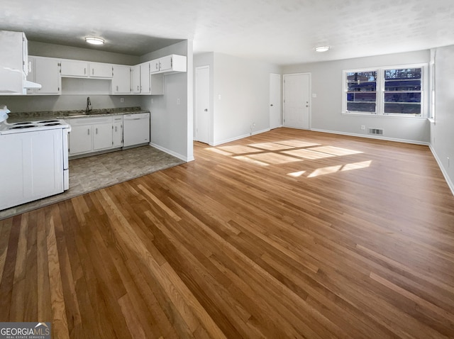 kitchen featuring white appliances, visible vents, light wood-style floors, white cabinetry, and a sink