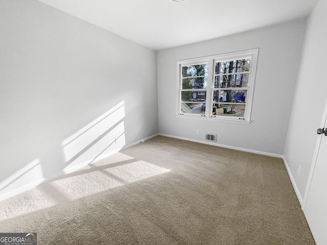 empty room featuring carpet, visible vents, and baseboards