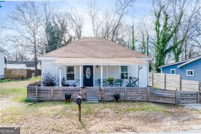 bungalow-style home with fence, a porch, and roof with shingles