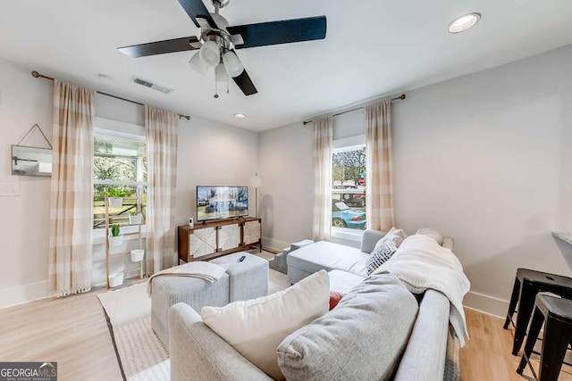 living room with visible vents, light wood-style flooring, and baseboards